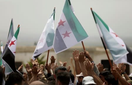 Displaced Syrians hold Free Syrian army flags during a protest calling for an end to the strikes and for Ankara to open the frontier at the Atmeh crossing on the Syrian-Turkish border, in Idlib governorate