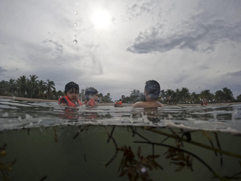 Galo Felipe Espinoza Sanchez, 5, left, swims with his dad and cousin at Crandon Park beach, during the family's visit to Florida from Ecuador and France, Friday, July 28, 2023, in Key Biscayne, Fla. Humans naturally look to water for a chance to refresh, but when water temperatures get too high, some of the appeal is lost. (AP Photo/Rebecca Blackwell)