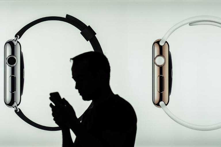 A man uses a smartphone in front of an Apple store display advertising the smartwatch in Hong Kong, on April 24, 2015