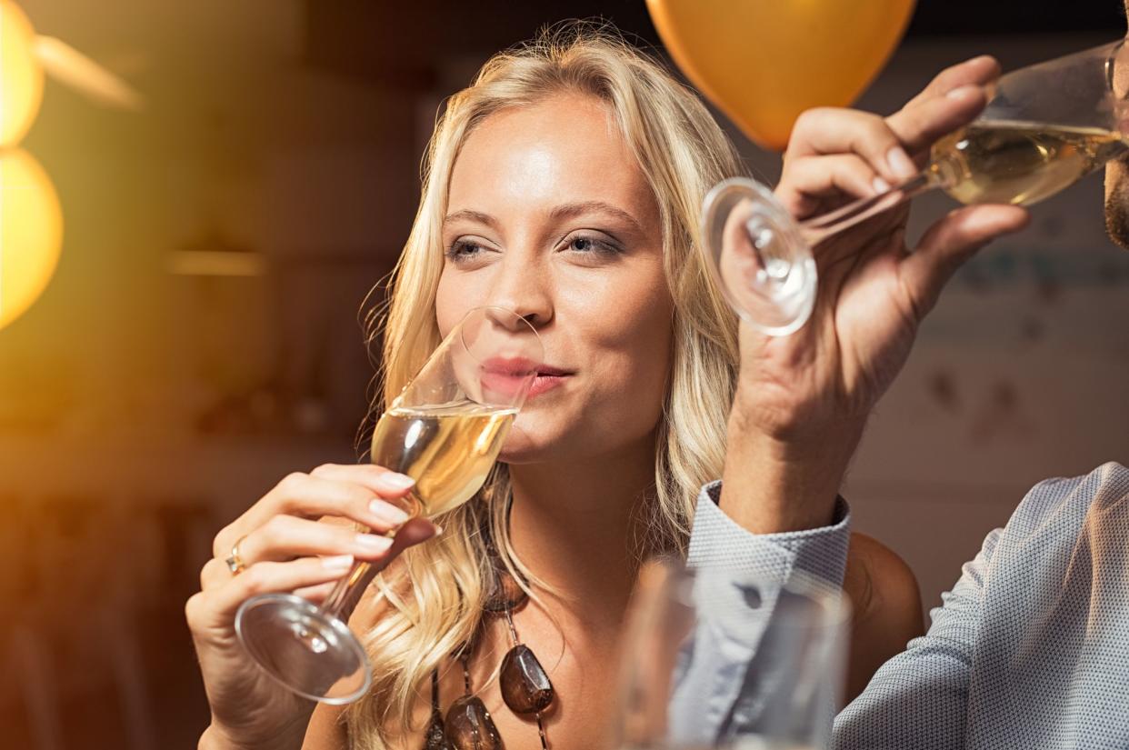 Young woman holding white wine glass and taking a sip