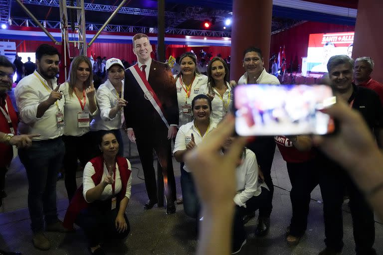 Seguidores de Santiago Peña, candidato presidencial del partido gobernante Colorado, posan para una foto con una figura recortada a tamaño real del candidato tras el cierre de la votación durante las elecciones generales en Asunción, Paraguay, el domingo 30 de abril de 2023. 