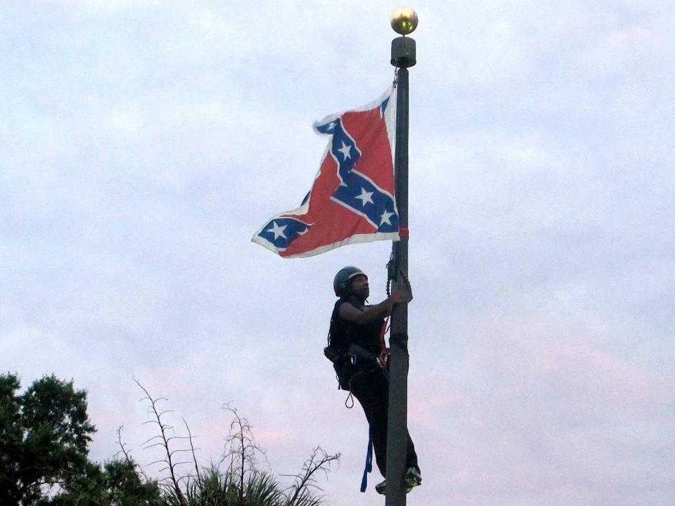 In this June, 27, 2015, file photo, Bree Newsome of Charlotte, N.C., climbs a flagpole to remove the Confederate battle flag at a Confederate monument in front of the Statehouse in Columbia, S.C. After nine black parishioners were slain at a Charleston church, South Carolina did what many thought would never happen: It moved the Confederate flag off Statehouse grounds.