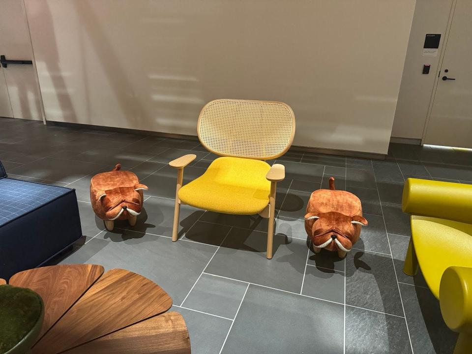 A yellow chair with two stools shaped like bulldogs on either side