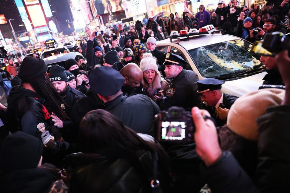 A scrimmage near a police car with a broken front windshield.