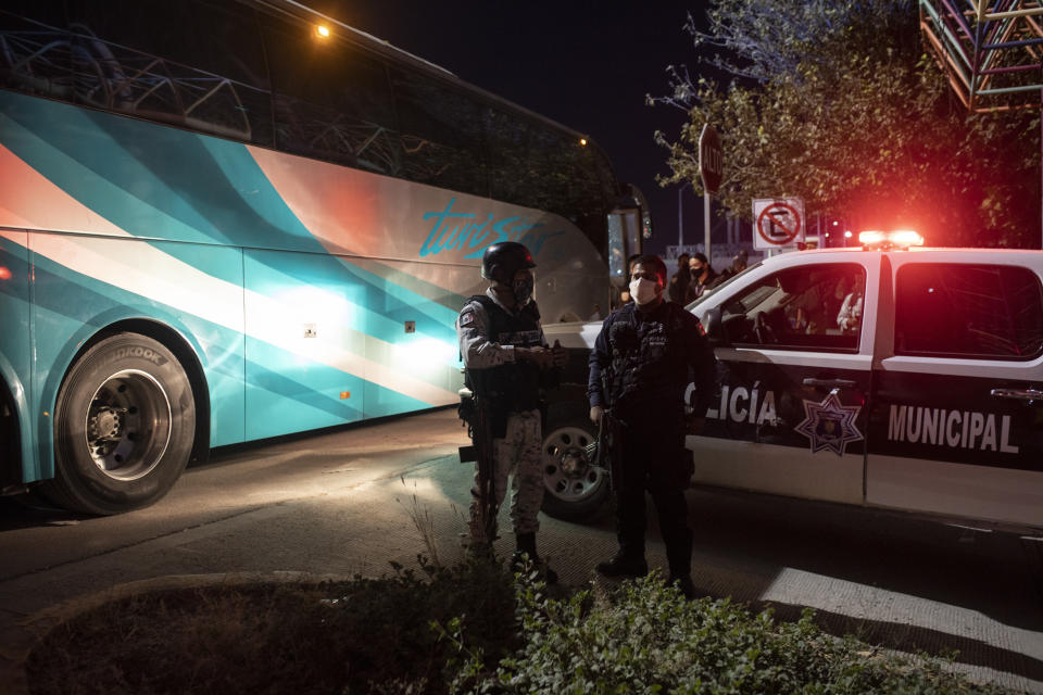 Mexican police and National Guard stand near a parked bus near the Rio Grande river in Ciudad Acuna, Mexico, at dawn Thursday, Sept. 23, 2021, on the border with Del Rio, Texas. Mexico has been ramping up efforts to relieve migrant numbers at this segment of the border. (AP Photo/Felix Marquez)