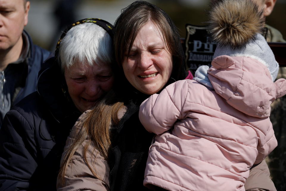 Tetiana, wife of Volodymyr Rurak, a soldier killed by Russian shelling in the town of Lyman in Donetsk Oblast, holds her daughter Oleksandra as she mourns by her husband's grave during his funeral at the Lychakiv cemetery, in Lviv, Ukraine, March 25, 2022. REUTERS/Zohra Bensemra