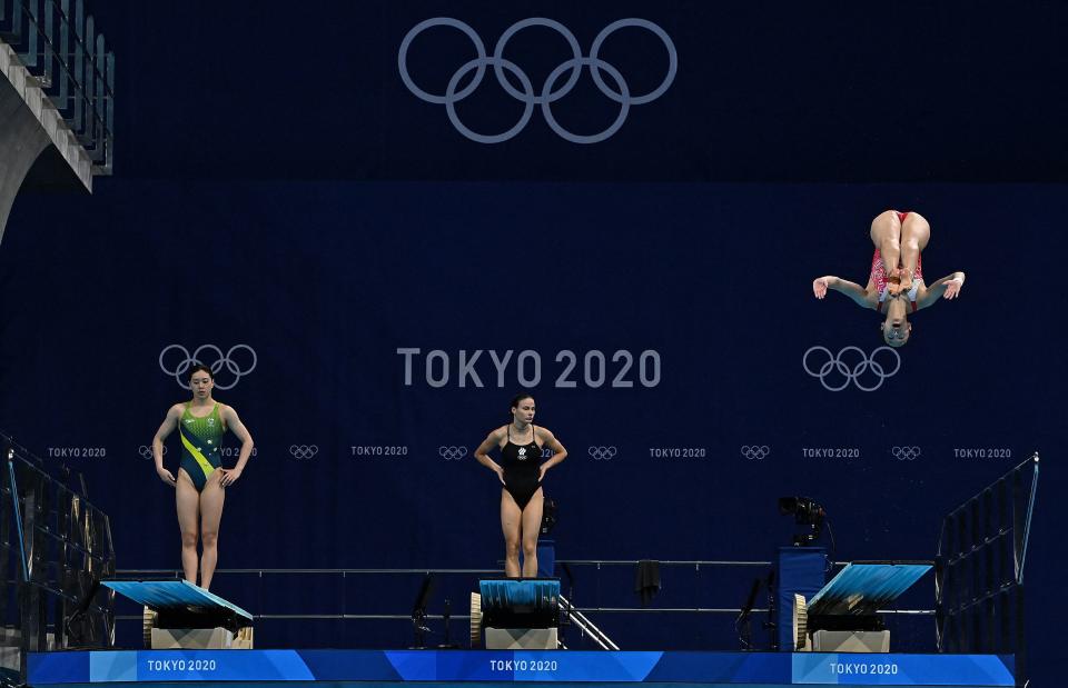 <p>Australia's Esther Qin (L) and Russia's Mariia Poliakova (C) wait as Switzerland's Michelle Heimberg competes in the women's 3m springboard diving final event during the Tokyo 2020 Olympic Games at the Tokyo Aquatics Centre in Tokyo on August 1, 2021. (Photo by Attila KISBENEDEK / AFP) (Photo by ATTILA KISBENEDEK/AFP via Getty Images)</p> 