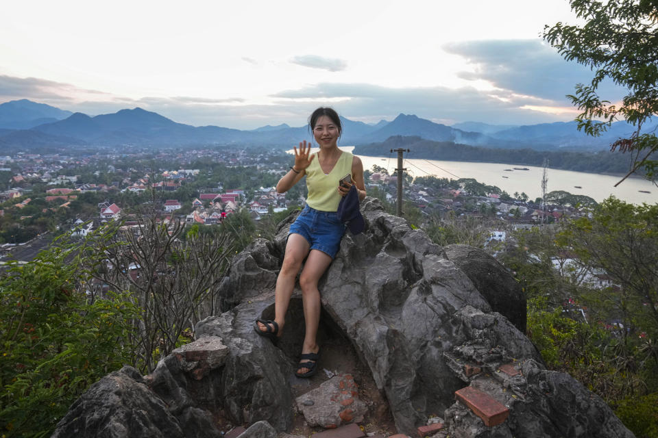 A tourist from China poses for a picture at Phousi Hill in Luang Prabang, Laos, Sunday, Jan. 28, 2024. Luang Prabang was named a UNESCO World Heritage Site nearly 30 years ago, but a multibillion-dollar dam project is raising questions that could deprive the city of its coveted status and prompting broader concerns the Mekong River could be ruined by multiple dams that are being planned.(AP Photo/Sakchai Lalit)
