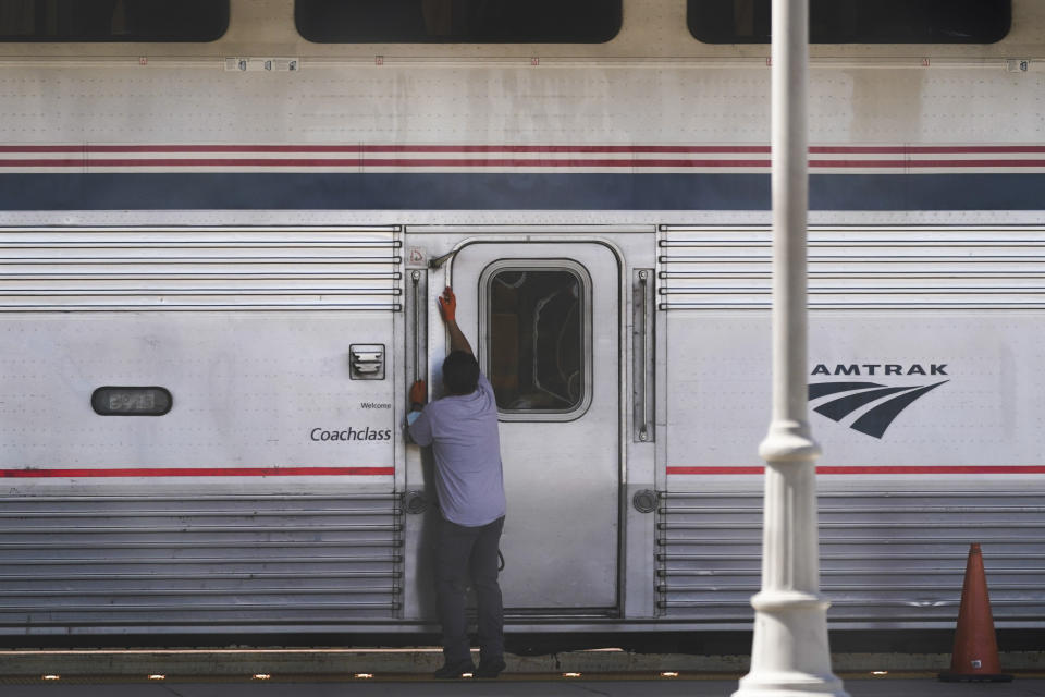 An Amtrak worker opens a door on a train at Union Station in Los Angeles as stoppages are announced on Wednesday, Sept. 14, 2022. Some Amtrak routes will be disrupted due to freight railroad labor negotiations. (AP Photo/Ashley Landis)