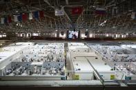 Medical workers and patients are seen in the treatment hall of a temporary hospital for coronavirus patients in the Krylatskoye Ice Palace in Moscow, Russia, Wednesday, Nov. 18, 2020. Russia’s health care system has been under severe strain in recent weeks, as a resurgence of the coronavirus pandemic has swept the country. (AP Photo/Pavel Golovkin)