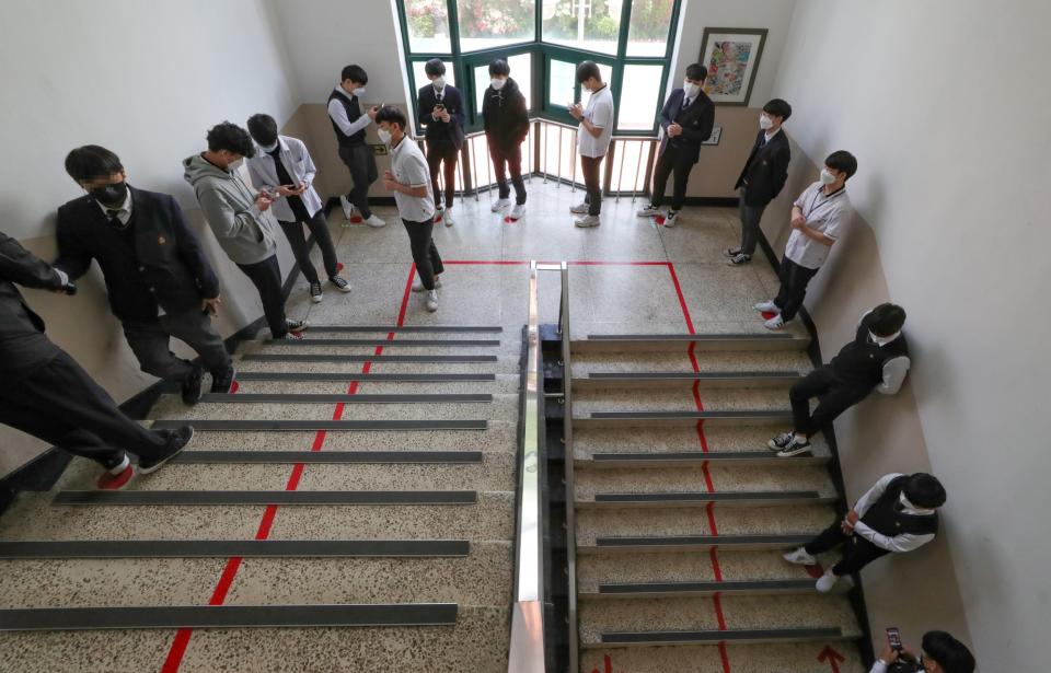 High school students wearing protective masks, queuing up to enter the cafeteria (via REUTERS)