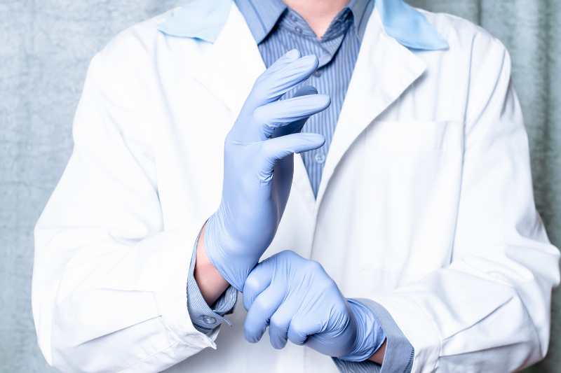 Person in Lab Coat Putting on Rubber Glove