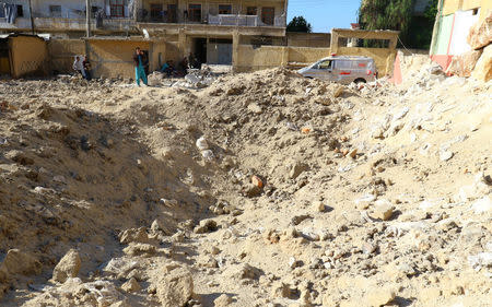 A medic stands near a crater outside a hospital that was hit by overnight airstrike, in Kafr Takharim, northwest of Idlib city, Syria April 25, 2017. REUTERS/Ammar Abdullah