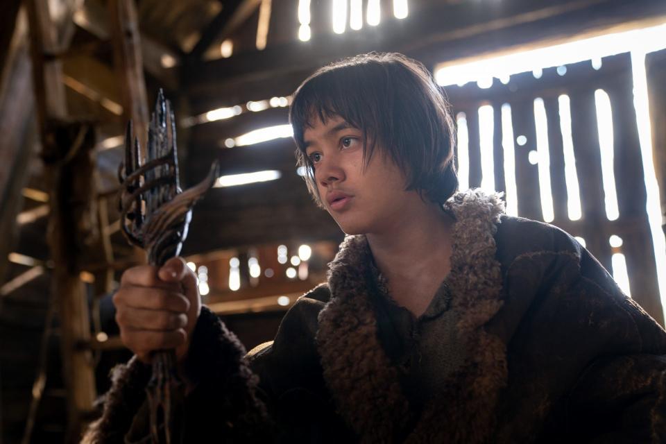 Tyroe Muhafidin as Theo holding the hilt of a sword in a still from The Lord of the Rings: The Rings of Power