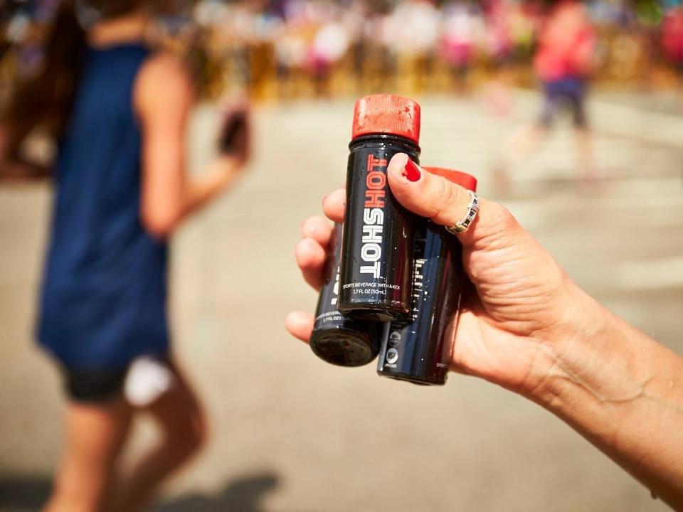 A hand holding three bottles of HotShot.