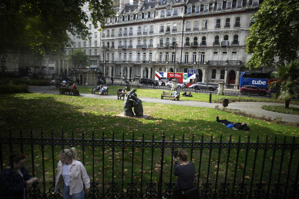 People take a break in a London park, Sunday, Sept. 11, 2022. On morning television, the moment was singularly somber — the departure of the hearse bearing the flag-draped coffin of Queen Elizabeth II. But at the very same hour, as fans in shorts and Ray-Bans streamed into London's Oval stadium for a long-anticipated cricket match, you wouldn't have guessed the country was preparing for the most royal of funerals. (AP Photo/Christophe Ena)