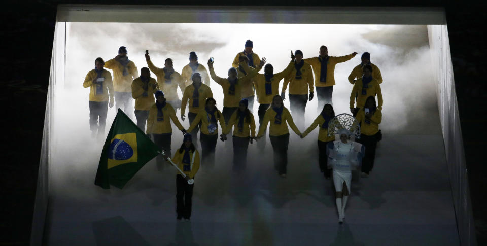 Jaqueline Mourao of Brazil holds the national flag and enters the stadium with her team during the opening ceremony of the 2014 Winter Olympics in Sochi, Russia, Friday, Feb. 7, 2014. (AP Photo/Charlie Riedel)