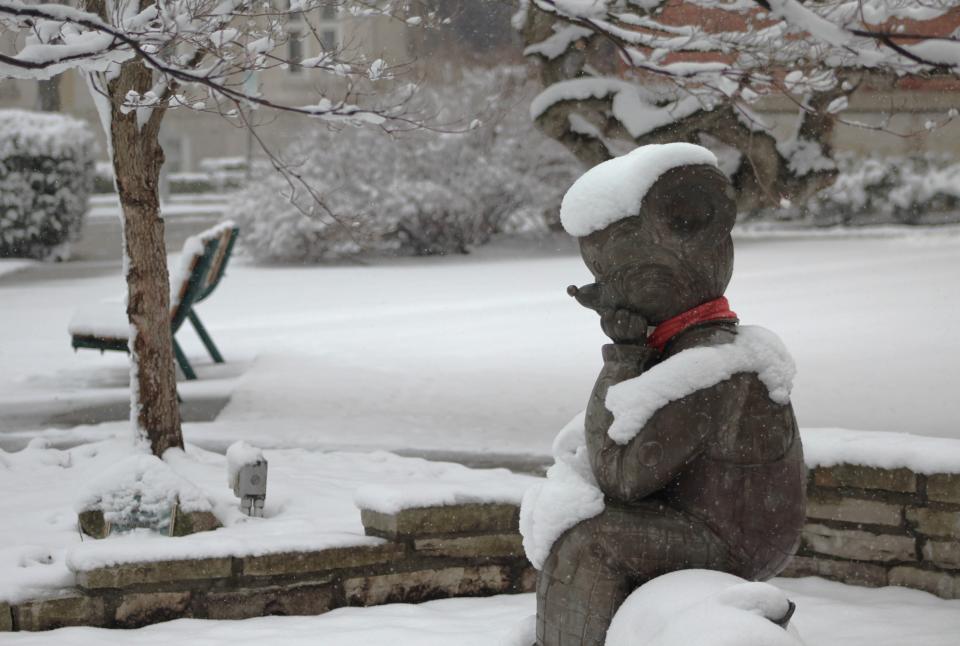 Snow surrounds a 4-foot-high bronze Little Brown Bear statue in front of Dorsch Memorial Library in downtown Monroe on Friday.