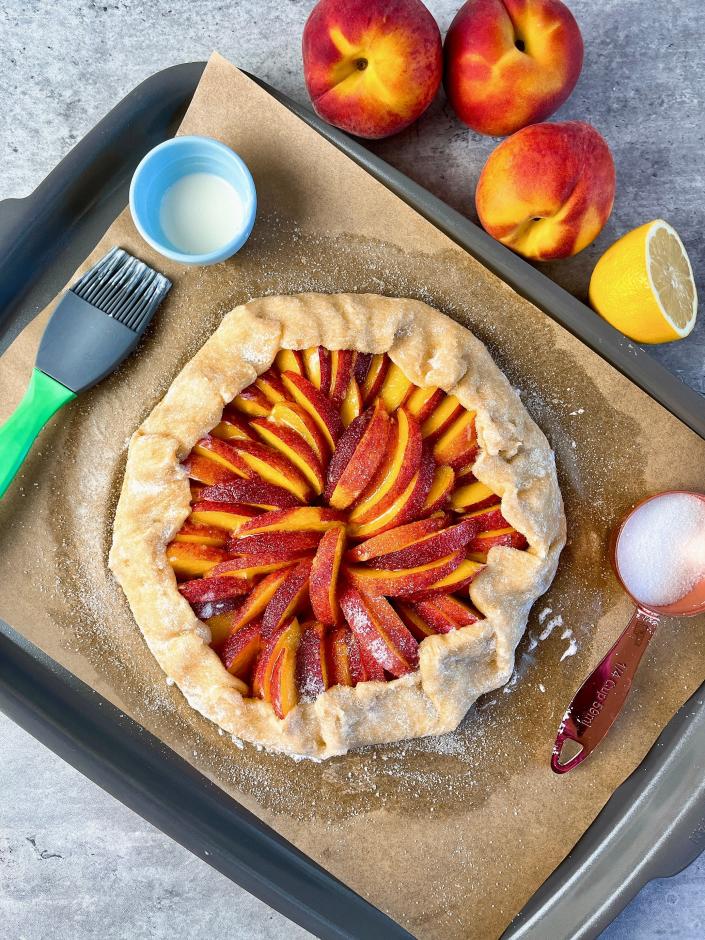 Brush heavy cream (or egg) all over the dough and sprinkle the peaches and crust with granulated sugar before baking.