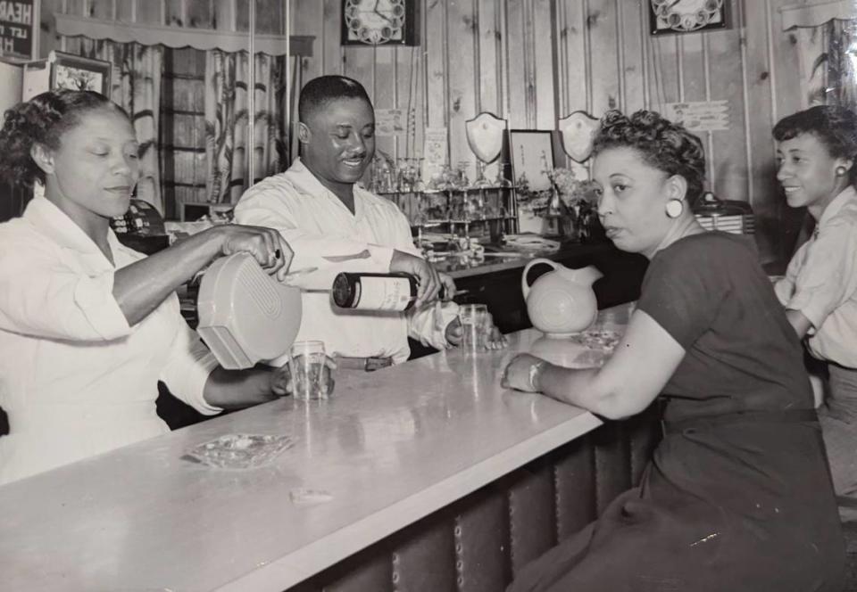 James McKee pours a drink for customers at the bar of his Excelsior Club in Charlotte. He and his wife opened the club in 1944.