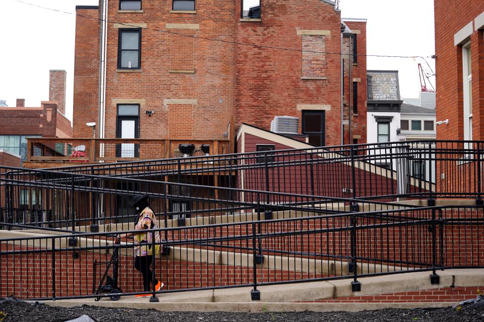 A patron of the Bobbie Sterne Health Center walks down a ramp in front of high-priced apartments, background, nestled to the right of the clinic.