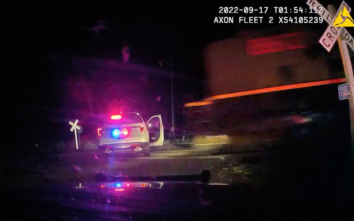 Screen grab of freight train approaching parked police car