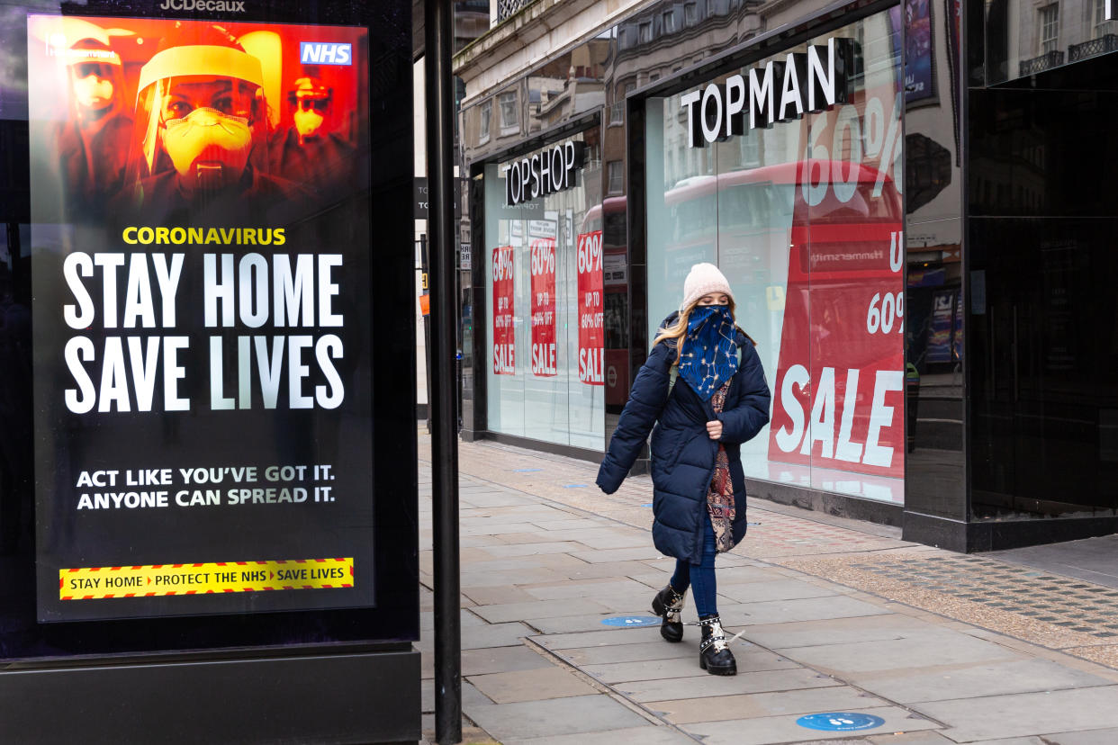 A woman in protective face mask is seen walking by the NHS 'Stay Home' poster as the UK's government introduced strict Coronavirus restrictions earlier this month due to sharp increase in numbers of Covid-19 cases in UK - London, England on January 11, 2021. Exercising  and going to work are the exceptions for Stay at Home policy. (Photo by Dominika Zarzycka/NurPhoto via Getty Images)