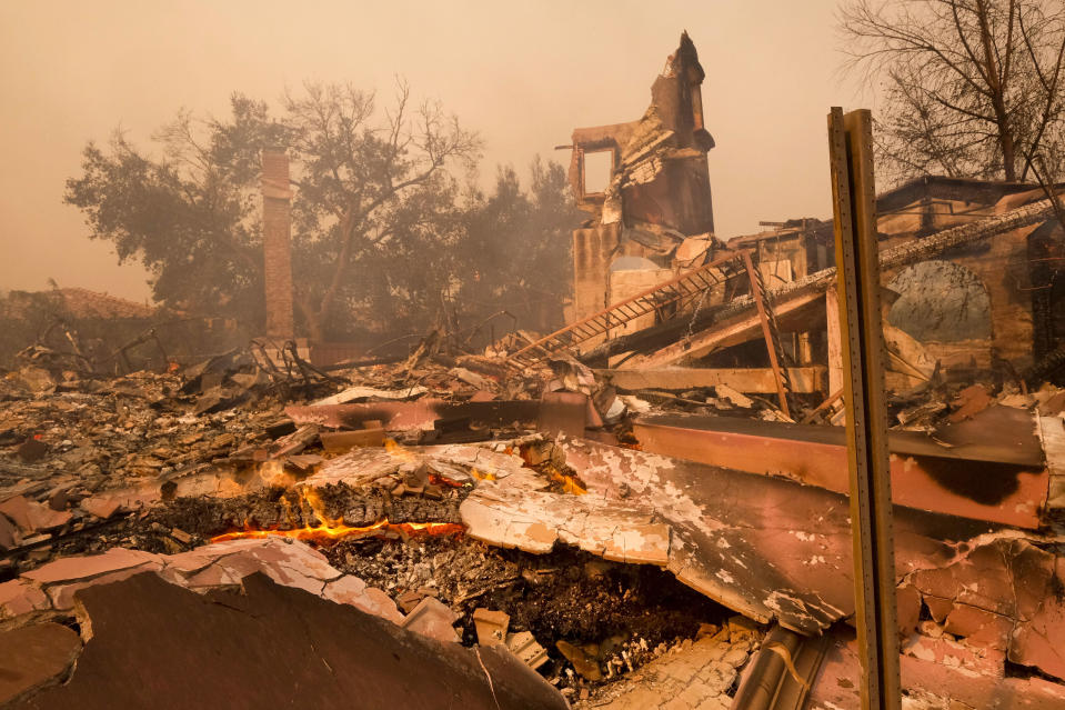 FILE - This Nov. 9, 2018 file photo shows the charred remains of a home after the Woolsey fire swept through Malibu, Calif. The number of structures destroyed by a huge Southern California wildfire has risen to 1,500. Another 341 structures were damaged as of a Monday, Nov. 19, 2018 count. As firefighters mop up, repair and restoration of utilities is continuing along with repopulation of areas evacuated when winds spread the fire earlier this month. Forecasters predict rain in the area by midweek. (AP Photo/Ringo H.W. Chiu, File)