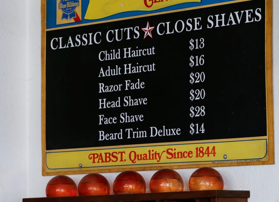 An old PBR advertising board with the current prices of haircuts at Barbershop Deluxe at 1206 E. Elm St. on Tuesday, Nov. 28, 2023.