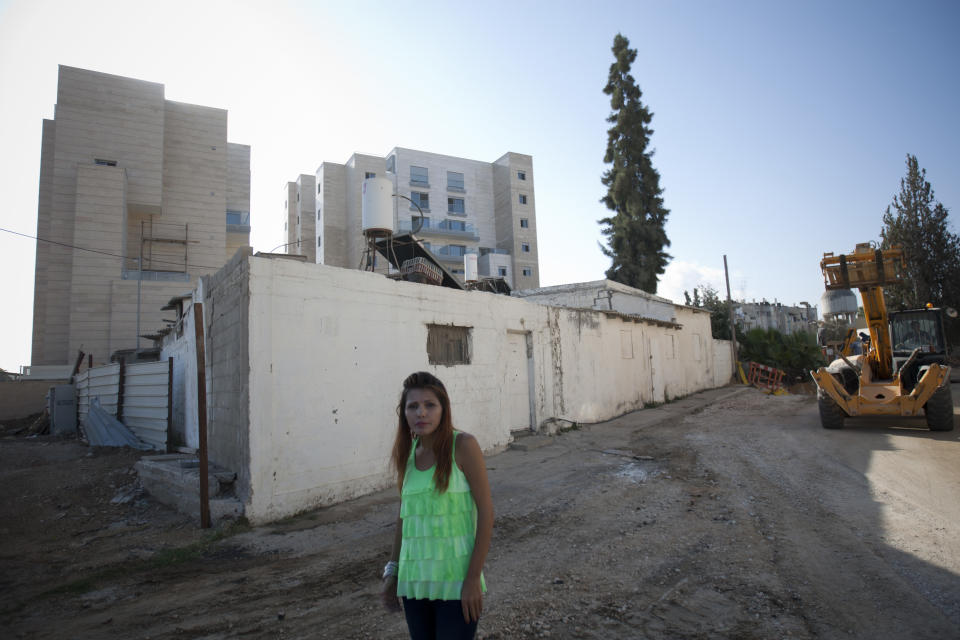 In this photo taken on Thursday, Sept. 20, 2012, Israeli Arab activist Horia Elsadi poses for a photograph in front of new housing project for religious Jews in Israel's mixed Arab-Jewish town of Lod, central Israel. Religious Jews who are the bedrock of the settlement movement have marked Israel's mixed Arab-Jewish cities as the new front to "reclaim," pushing into Arab neighborhoods to cement the Jewish presence there. The migration of several thousand devout Jews to rundown areas of Jaffa, Lod, Ramle and Acco has had a divisive effect far outweighing their absolute numbers, with Jews celebrating _ and Arab activists eyeing with mistrust and resentment _ the construction of Jewish seminaries and housing developments marketed exclusively to Jews. (AP Photo/Ariel Schalit)