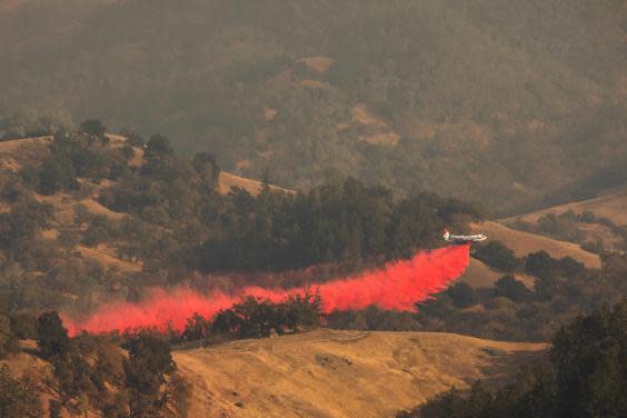 An air tanker drops fire retardant in the valley below in Healdsburg, California, on 26 October 2019 (AFP/Getty)