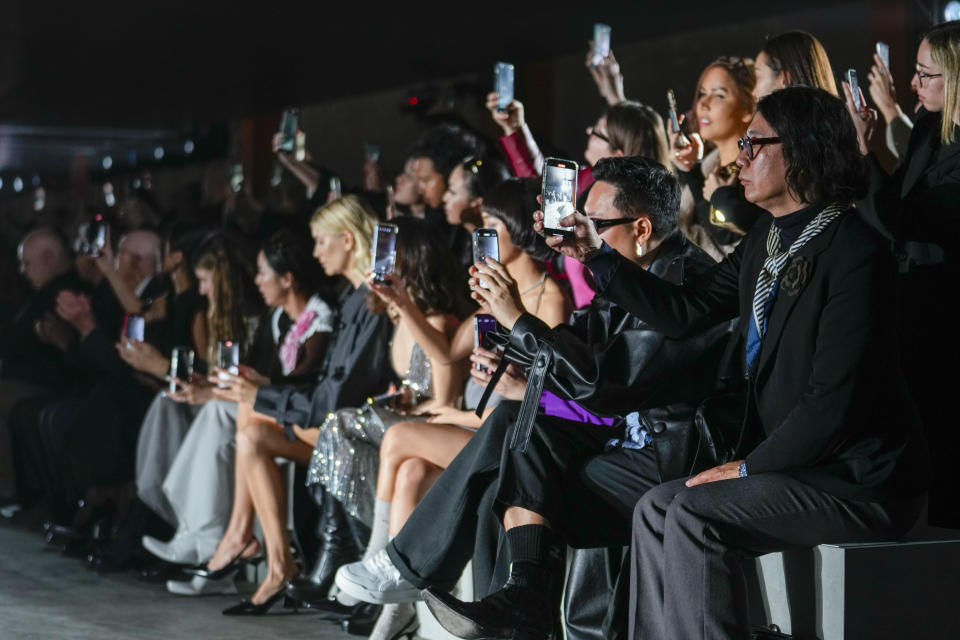 Audience members use their iPhones during the Prada women's Fall-Winter 2023-24 collection presented in Milan, Italy, Thursday, Feb. 23, 2023. (AP Photo/Luca Bruno)