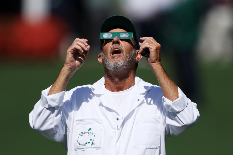 AUGUSTA, GEORGIA - APRIL 08: A caddie uses glasses to view the eclipse during a practice round prior to the 2024 Masters Tournament at Augusta National Golf Club on April 08, 2024 in Augusta, Georgia. (Photo by Warren Little/Getty Images)