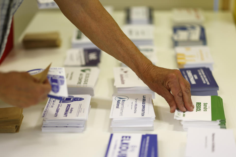 A voter picks up ballots at a voting station in Strasbourg, eastern France, Sunday June 12, 2022. Sunday, June 12, 2022. French voters are choosing lawmakers in a parliamentary election as President Emmanuel Macron seeks to secure his majority while under growing threat from a leftist coalition. (AP Photo/Jean-Francois Badias)