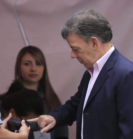 Colombia's president and presidential candidate Juan Manuel Santos checks his fingerprint before casting his vote in Bogota June 15, 2014. REUTERS/Jose Miguel Gomez