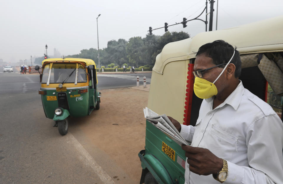 A three wheeler driver waits for passengers at a crossing wearing a pollution mask in New Delhi, India, Thursday, Nov. 7, 2019. The air quality index stood at 273 on Thursday in the capital after authorities declared a health emergency last weekend when the index crossed 500 — 10 times the level considered healthy by WHO standards. (AP Photo/Manish Swarup)