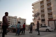 People stand in front of an apartment building which was damaged by a rocket fired from Syria, in Nusaybin