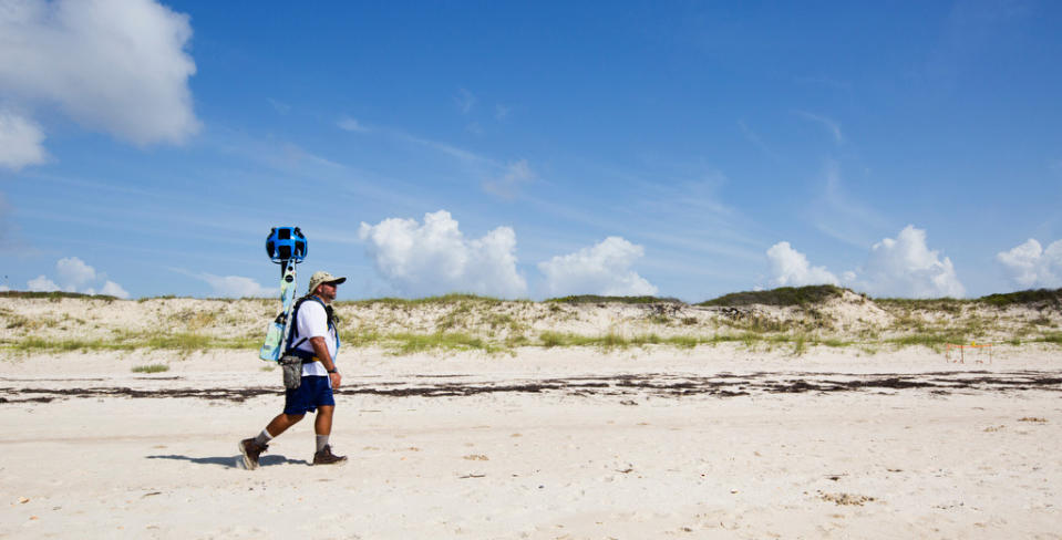 In this photo taken July 30, 2013, and made available by Visit Florida, Gregg Matthews carries a Google street view camera as he walks recording St. George Island sand dunes in the Florida Panhandle. Visit Florida, the state's tourism agency, partnered with Google in the effort to map all 825 miles of Florida’s beaches. The Florida project is the first large-scale beach mapping project. (AP Photo/Visit Florida, Colin Hackley)