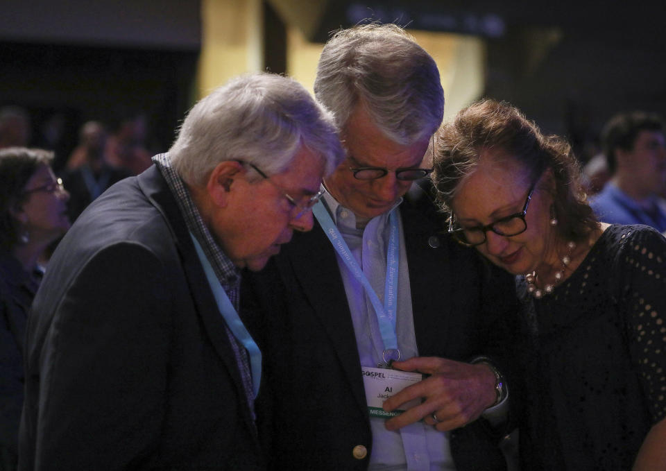 FILE - In this Wednesday, June 12, 2019 file photo, from left, Dick Lane, Al Jackson and his wife, Kem Jackson, pray on the second day of the Southern Baptist Convention's annual meeting in Birmingham, Ala. "The reason we're here is because we trust Jesus," his wife Kem Jackson said. As Southern Baptists prepare for their biggest annual meeting in more than a quarter-century in June 2021, accusations that leaders have shielded churches from claims of sexual abuse and simmering tensions around race threaten to once again mire the nation’s largest Protestant denomination in a conflict that can look more political than theological. ( Jon Shapley/Houston Chronicle via AP, File)