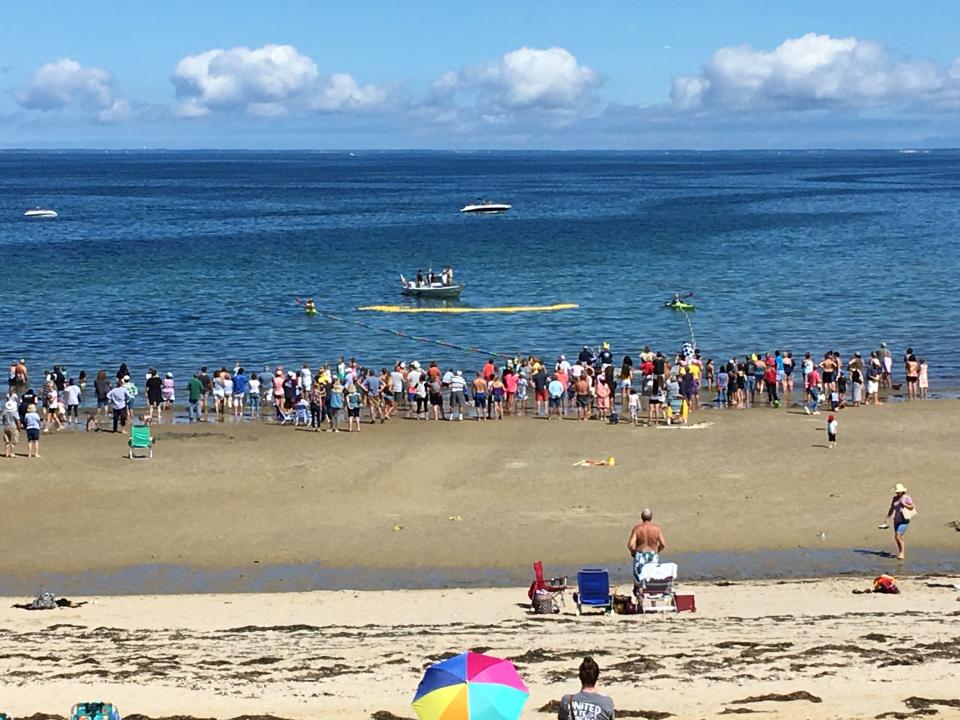 A crowd awaits the arrival of a fleet of yellow rubber ducks during the annual Rubber Duck Regatta at Corporation Beach.