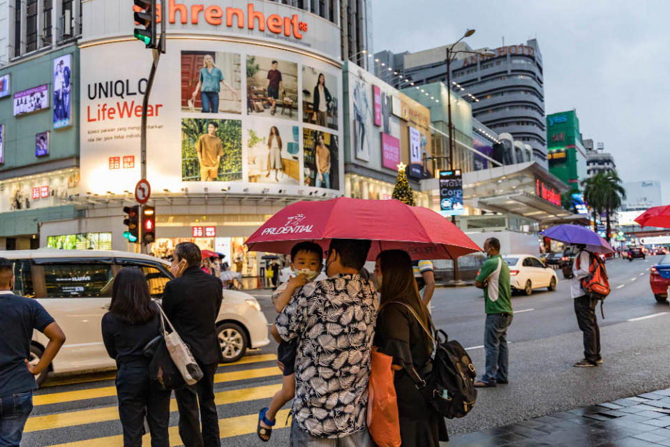 People hold umbrellas as they wait to cross at a traffic light during a rainy day in Kuala Lumpur January 2, 2022. &#x002014; Picture by Firdaus Latif