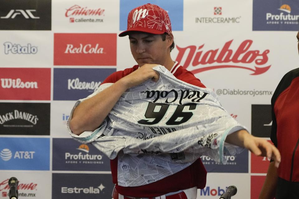 Trevor Bauer se pone una franela en su ceremonia de presentación como nuevo lanzador de los Diablos Rojos de México, en la Ciudad de México, el viernes 22 de marzo de 2024. (AP Foto/Fernando Llano)