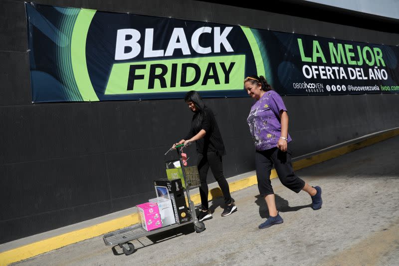 People leave a shop with purchases during the Black Friday sales in Caracas