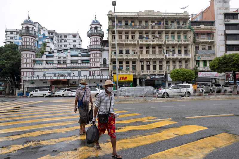 Men cross a street amid pandemic after authorities announced a stay-at-home order in Yangon
