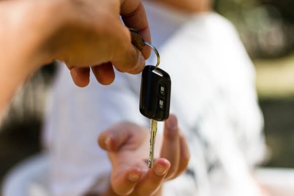 A set of car keys being passed from one person to another