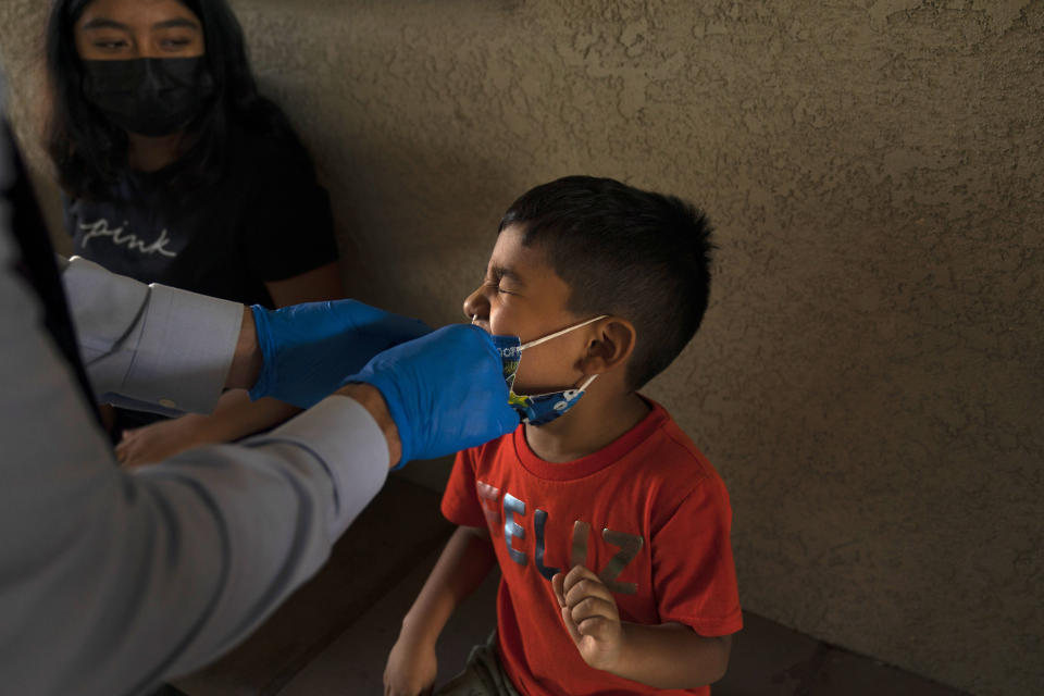 Shahir Sanchez, 5, grimaces as Dr. Neal Schwartz collects a nasal swab sample for COVID-19 testing at Families Together of Orange County Thursday, Aug. 26, 2021, in Tustin, Calif. (AP Photo/Jae C. Hong)