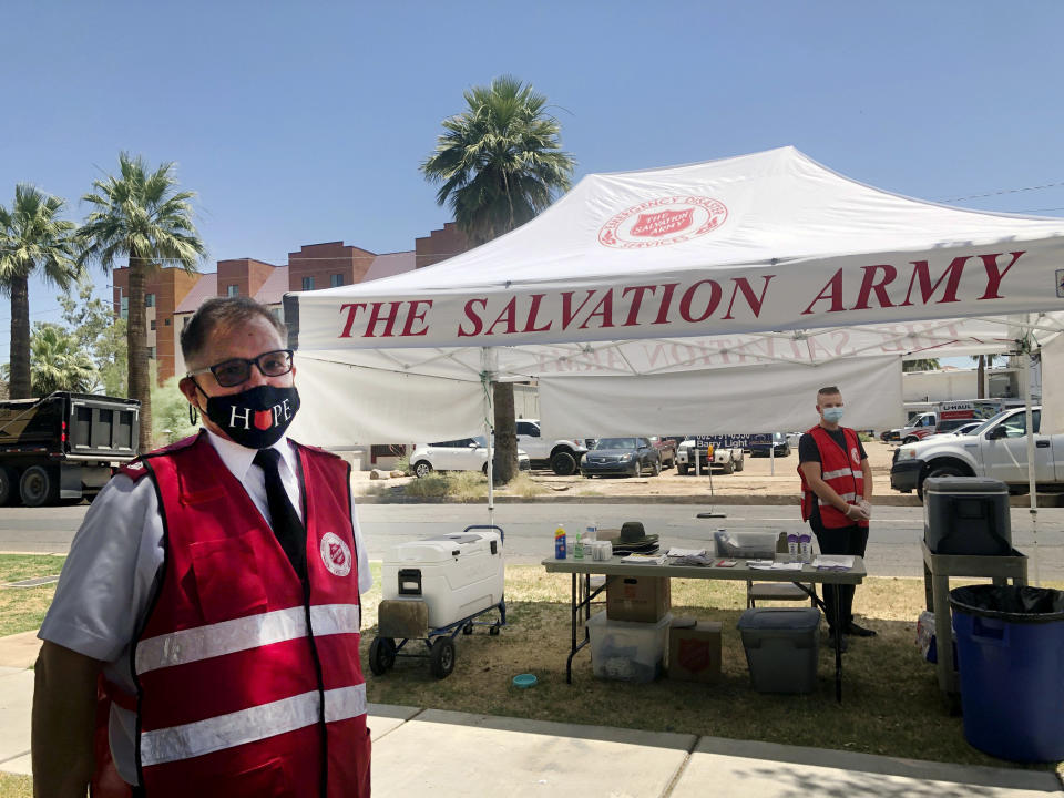 Salvation Army Maj. David Yardley, left, stands outside the Salvation Army Phoenix downtown headquarters where a heat relief station was set up on Thursday, May 28, 2020, in Phoenix, Ariz. A heat relief station offering cold water and a cool place inside to rest out of the brutal sun will be open every day through Sunday while an excessive heat warning is in effect. (AP Photo/Anita Snow)