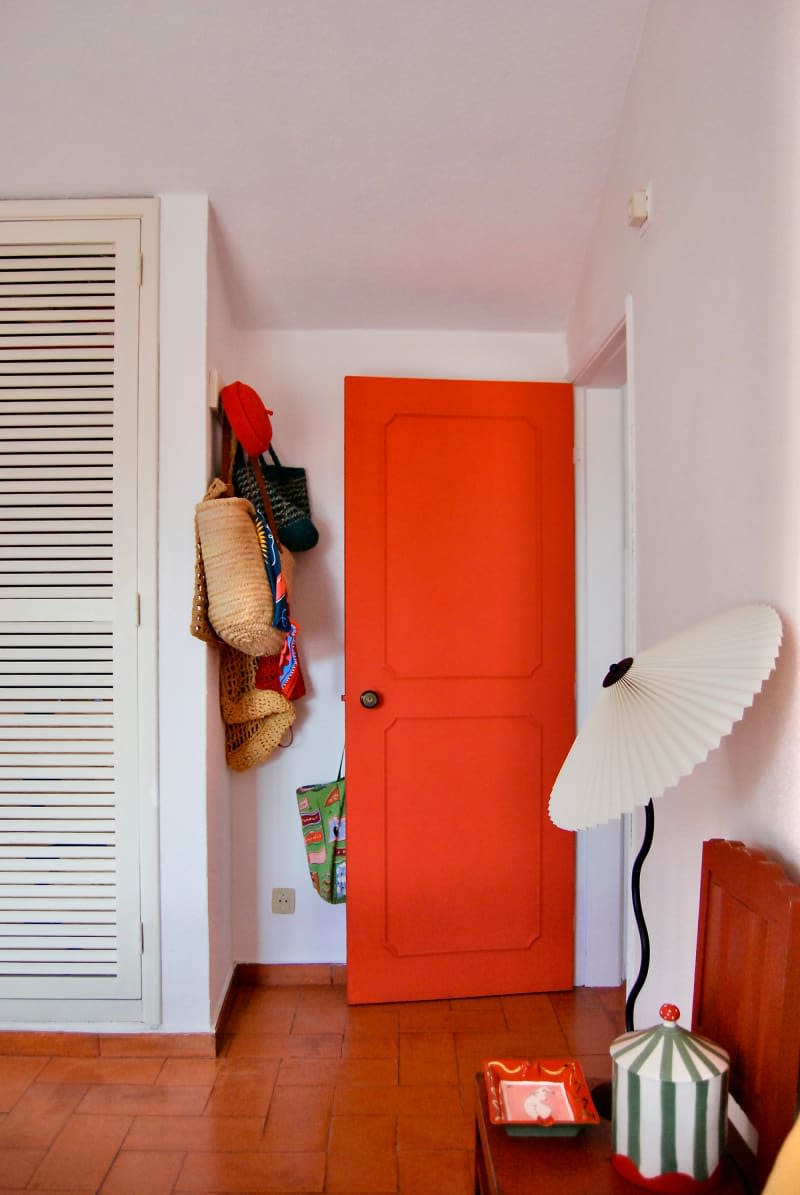 Red door in white bedroom with parasol.