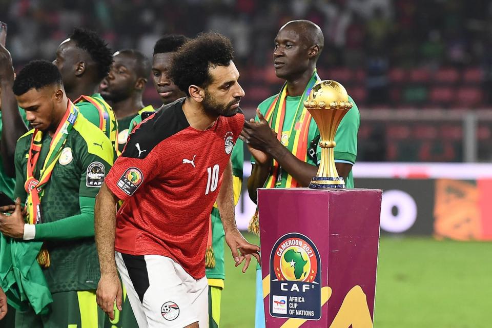 Salah walks past the trophy after Senegal’s triumph on penalties (AFP via Getty Images)