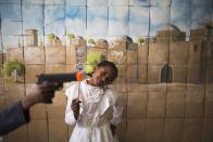 Nos vamos a Oriente Próximo, a una instantánea que podría malentenderse, pero no deja de ser inocente: un crío levanta una pistola de juguete mientras una niña se viste tradicionalmente junto a un mural de Jerusalén, durante la festividad judía del Purim en su escuela de Sderot, junto a Gaza. Sonríe a pesar de que 60 cohetes fueran disparados en la localidad días antes por la Jihad islámica. La costumbre les hace endurecerse. (REUTERS/Amir Cohen)